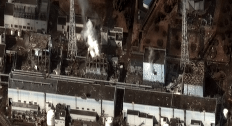 Vue aérienne d'une centrale nucléaire endommagée d'où s'échappe de la fumée